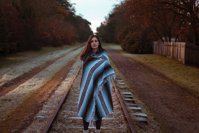 女人用蓝色和黑色的条纹围巾站在布朗火车铁路白天
